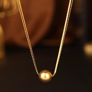 Gold double-layered necklace featuring a snake chain and a polished sphere pendant