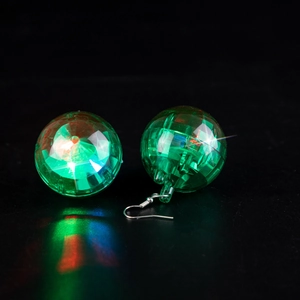 Macro shot of green faceted disco ball earrings with internal light on black background