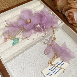 Détail d'une pince à cheveux fleur en organza lavande avec pompons en perles et feuille