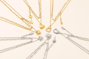 Flat lay of multiple double-layer heart pendant necklaces in gold and silver steel finish