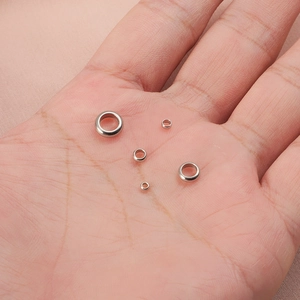 Polished silver stainless steel spacer beads in various sizes displayed on a hand