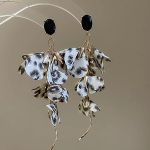 Detail view of leopard print fabric flower earrings with gold chains and black gemstone