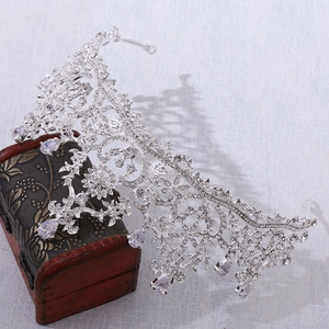 Detailed view of silver tiara with AAA zircons leaning on a vintage wooden jewelry box