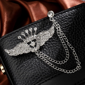 Detailed close-up of silver crown wing brooch with sparkling rhinestones and tassels