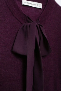 Détail d'un haut en maille violet foncé avec un nœud élégant en mousseline