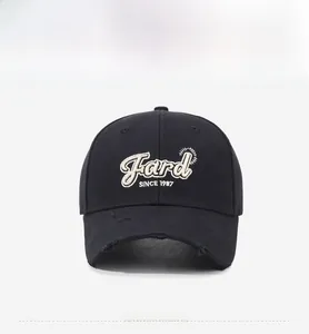 Detailed macro shot of distressed brim and white letter embroidery on black baseball cap