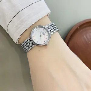 Minimalist women's quartz watch with silver mesh strap and pearl dial on wrist