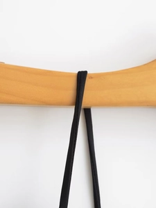 Detailed close-up of slim black spaghetti straps with high-density stitching on satin dress