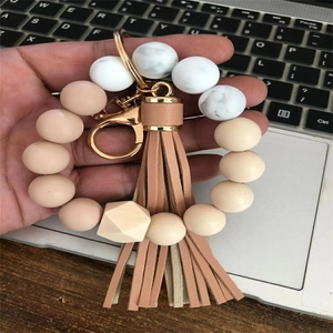 Detail of beaded wristlet keychain with marble silicone beads and beige leather tassel