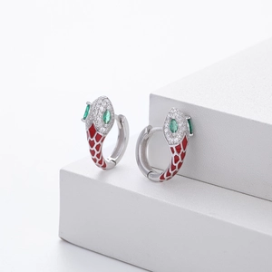 Detail of silver snake hoop earrings with red enamel scales and green zircon eyes