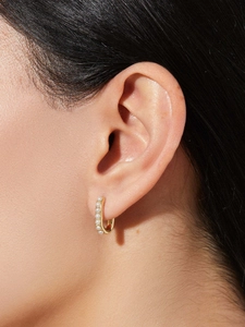 Close-up of a model wearing a gold U-shaped hoop earring with embedded pearls