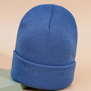 Texture détaillée d'un bonnet en tricot bleu avec revers sur un support géométrique