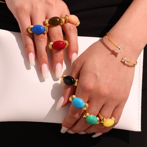Chic gold-plated cuff with resin oval stone rings in vibrant candy colors on hands
