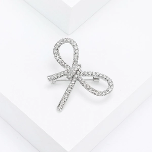 Macro shot of silver rhinestone bow brooch on white geometric prop for clothes