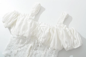 Detailed view of white lace crop top with ruffle accents and front bow tie detail