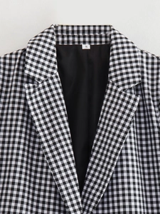 Detailed view of the notch lapel and black lining of a black and white checkered blazer