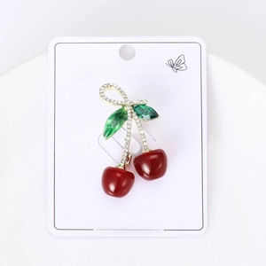 Close-up of red cherry brooch with green gemstone leaves and crystal-inlaid gold stem