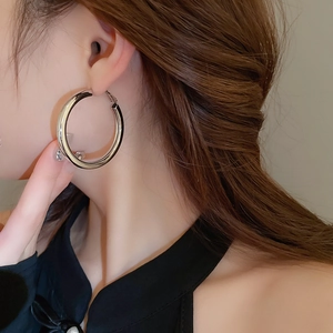 Close-up of large polished silver hoop earrings worn by a model in warm light