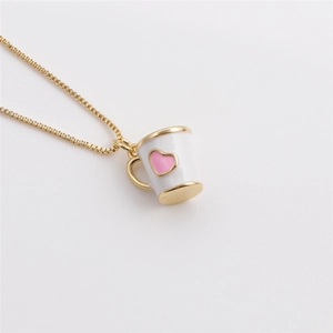 Macro shot of a gold-plated necklace with a white mug pendant and pink heart detail