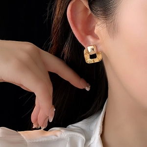 Side view of model wearing gold square wrinkled earrings with metallic texture