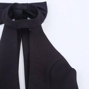 Détail de l'élégant col licou avec nœud sur une mini-robe noire ajustée