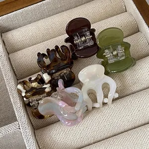 Set of 6 mini acetate hair claw clips in solid colors and marble patterns on velvet tray