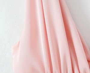 Détail du tissu rose lisse avec des plis doux et un léger éclat pour une mini robe rose