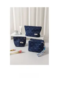 Three-piece denim makeup bag set with white bow and heart patterns in lifestyle setting