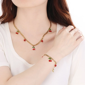Detail of 18K gold-plated cherry necklace and bracelet set worn on a female model
