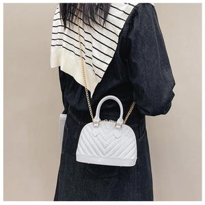 Detailed view of white jelly crossbody bag with gold chain strap on a denim outfit