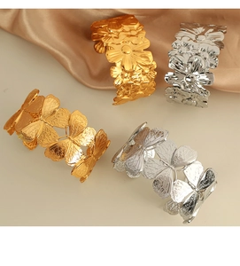 Detail view of 18K gold and silver butterfly and flower wide cuffs in polished titanium steel
