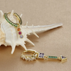 Detail of gold drop earrings with colorful zircon on silk and white seashell