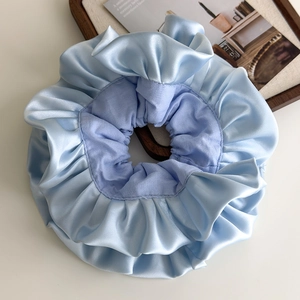 Macro shot of light blue double-layered satin scrunchie with pleated ballet-style texture