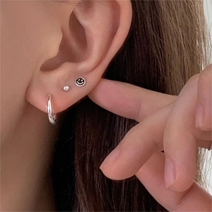 Macro shot of 925 silver earring set featuring smiley face and minimalist stud designs
