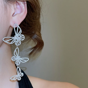 Macro detail of asymmetric silver long butterfly drop earrings with cubic zirconia inlay