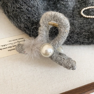 Detailansicht der Haarspange mit grauem Strickgarn, Pelzball und weißer Perle für Winter