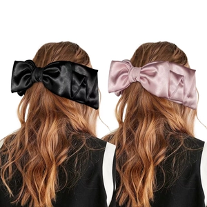 Dual view of large silk bow hair clips in black and pink worn on models back of heads