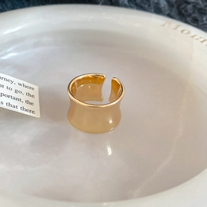 Close-up of wide gold-plated open ring with polished finish on marble background