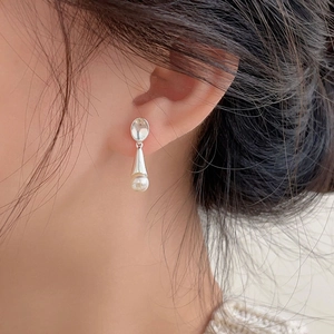 Close-up of a model wearing a drop-shaped white pearl earring with silver base