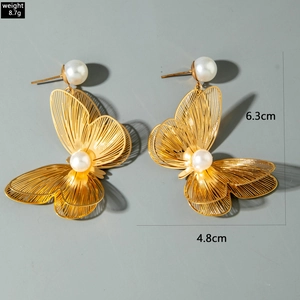 Detail view of large gold hollow butterfly earrings with white pearls and size measurements