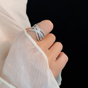 Detail of multi-layer crossover silver ring with zircon stones on a model's finger