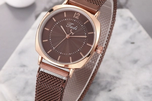 Détail de la montre à quartz rose dorée avec cadran brun ondulé et bracelet en maille milanaise