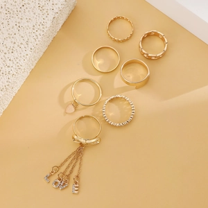 Detailed view of 7pcs gold ring set with LOVE charms, tassels and rhinestone accents