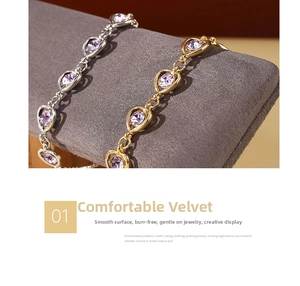 Detail of grey velvet jewelry tray showcasing gold and silver heart-shaped bracelets