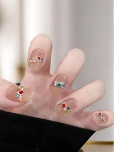 Macro shot of jelly nude press-on nails featuring colorful rhinestones and pearls