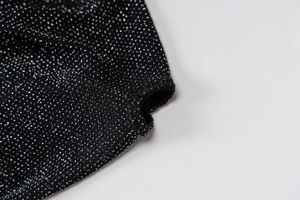 Gros plan sur un tissu noir métallisé avec des fibres pailletées argentées fines