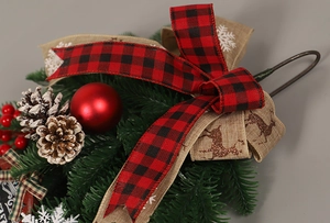Détail d'une couronne de Noël avec pommes de pin, boules rouges et nœud écossais