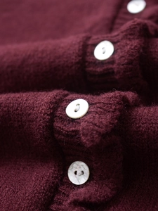 Macro detail of wine red long-hair knit cardigan with pearlescent white buttons
