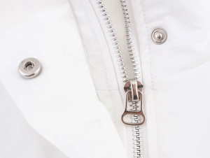 Close-up of silver metal zipper and snap buttons on a white high-neck utility jacket