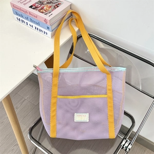 Détail du grand sac cabas en maille violette avec des anses jaunes sur une chaise